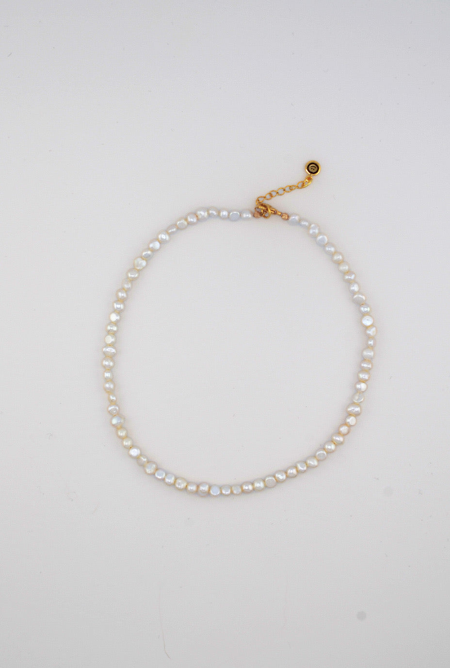 A delicate handmade freshwater pearl choker with organic-shaped pearls and a gold extender chain for an adjustable fit.