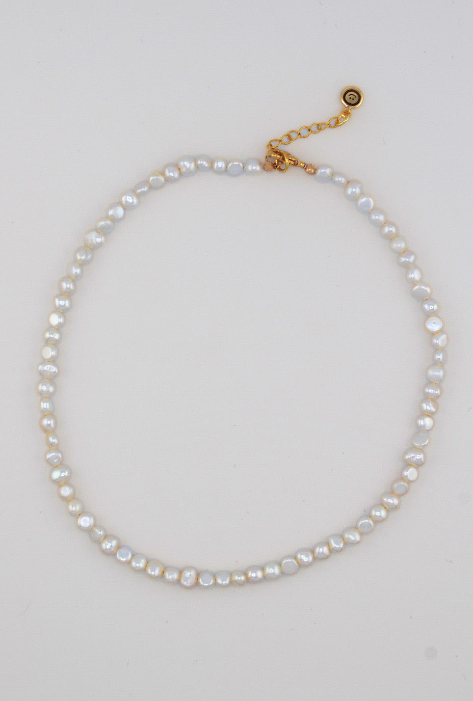 A close-up of the pearl choker highlighting its luminous freshwater pearls and elegant gold clasp for a timeless finish.