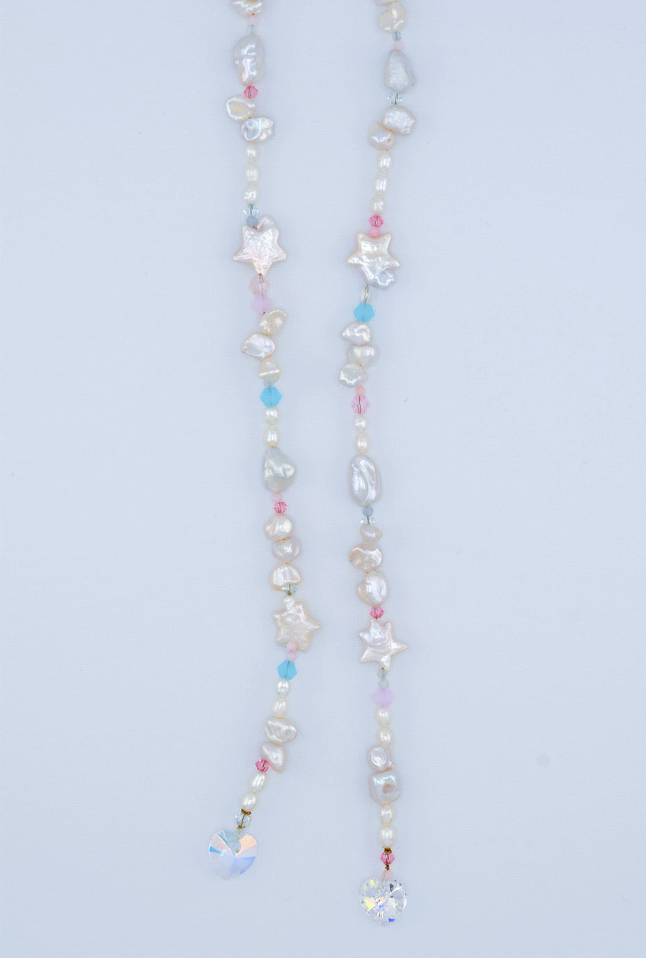 The bottom half of the handcrafted pearl and crystal hair accessory in the shape of a bow, featuring an organic arrangement of freshwater pearls and pink and blue Austrian glass crystals for a sophisticated and romantic touch