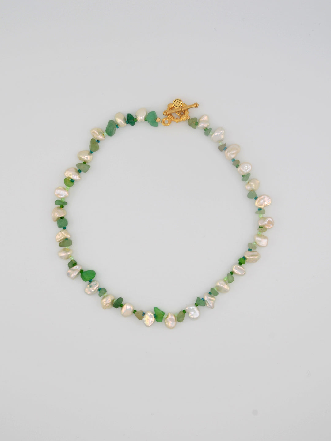 A delicate handmade necklace featuring lustrous freshwater keshi pearls paired with smooth green aventurine crystal chips. This piece is finished with a gold-tone clasp and is perfect for adding a touch of natural beauty to any outfit.