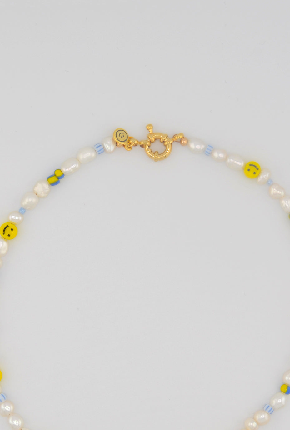 Another close up shot of the playful choker featuring a combination of freshwater pearls, smiley face beads, and pastel-colored accents, secured with a golden clasp