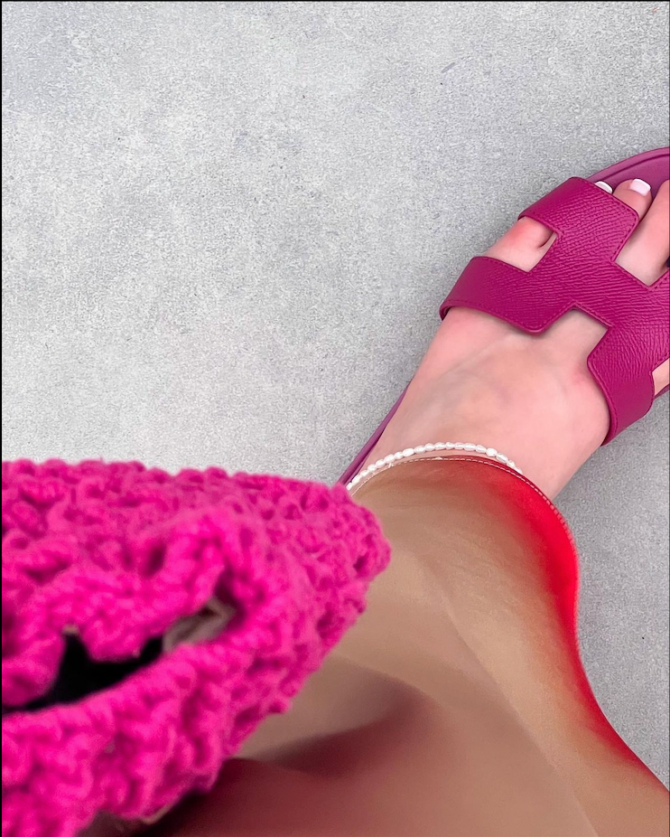 A close-up of a foot wearing the fashionable anklet with pearls, paired with a vibrant purple sandal, giving off a playful summer vibe.