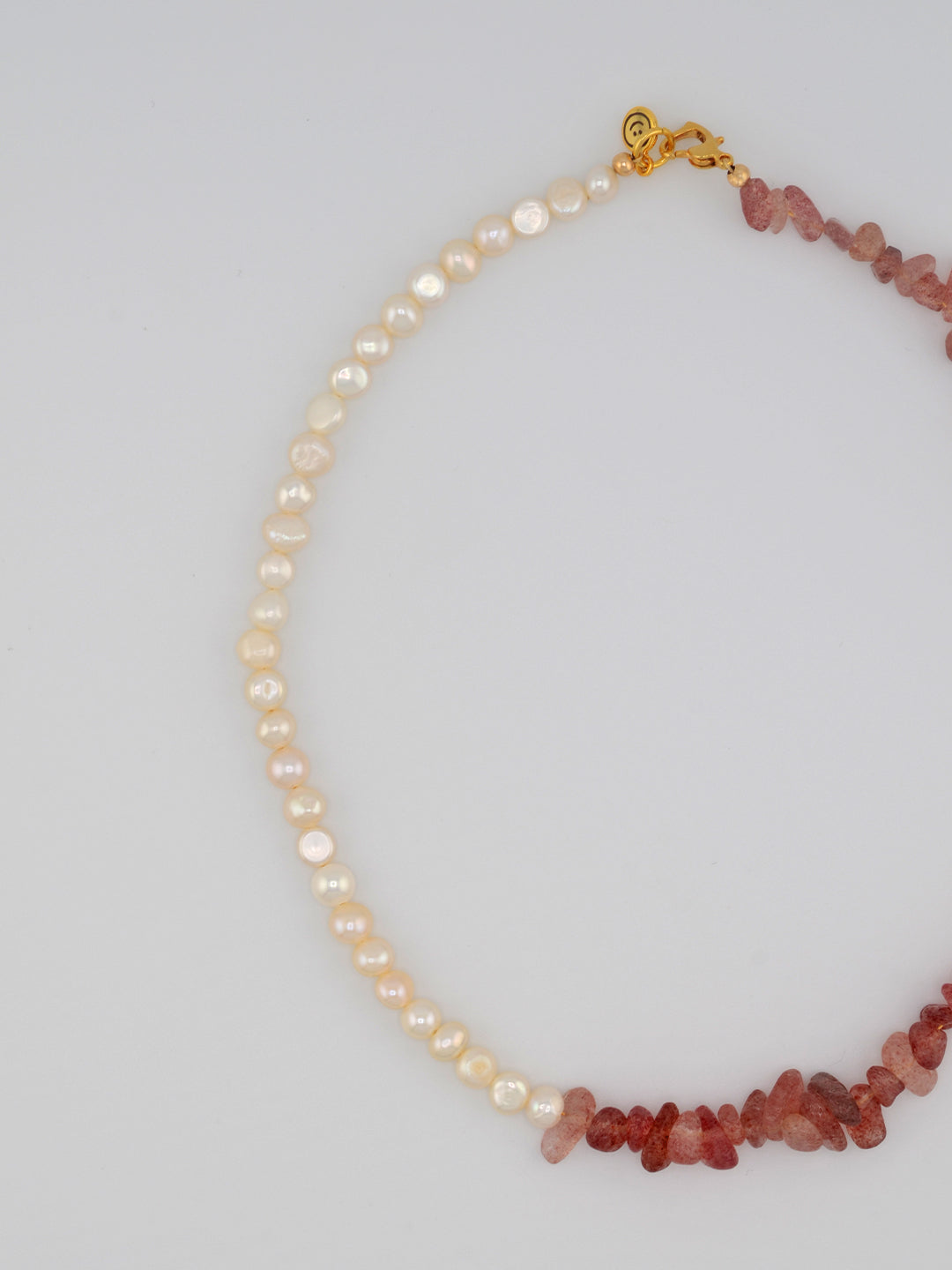 This elegant necklace features smooth freshwater pearls, interspersed with raw strawberry quartz crystal chunks, offering a textured look that blends natural beauty with an elegant touch. Finished with a delicate gold-tone clasp.