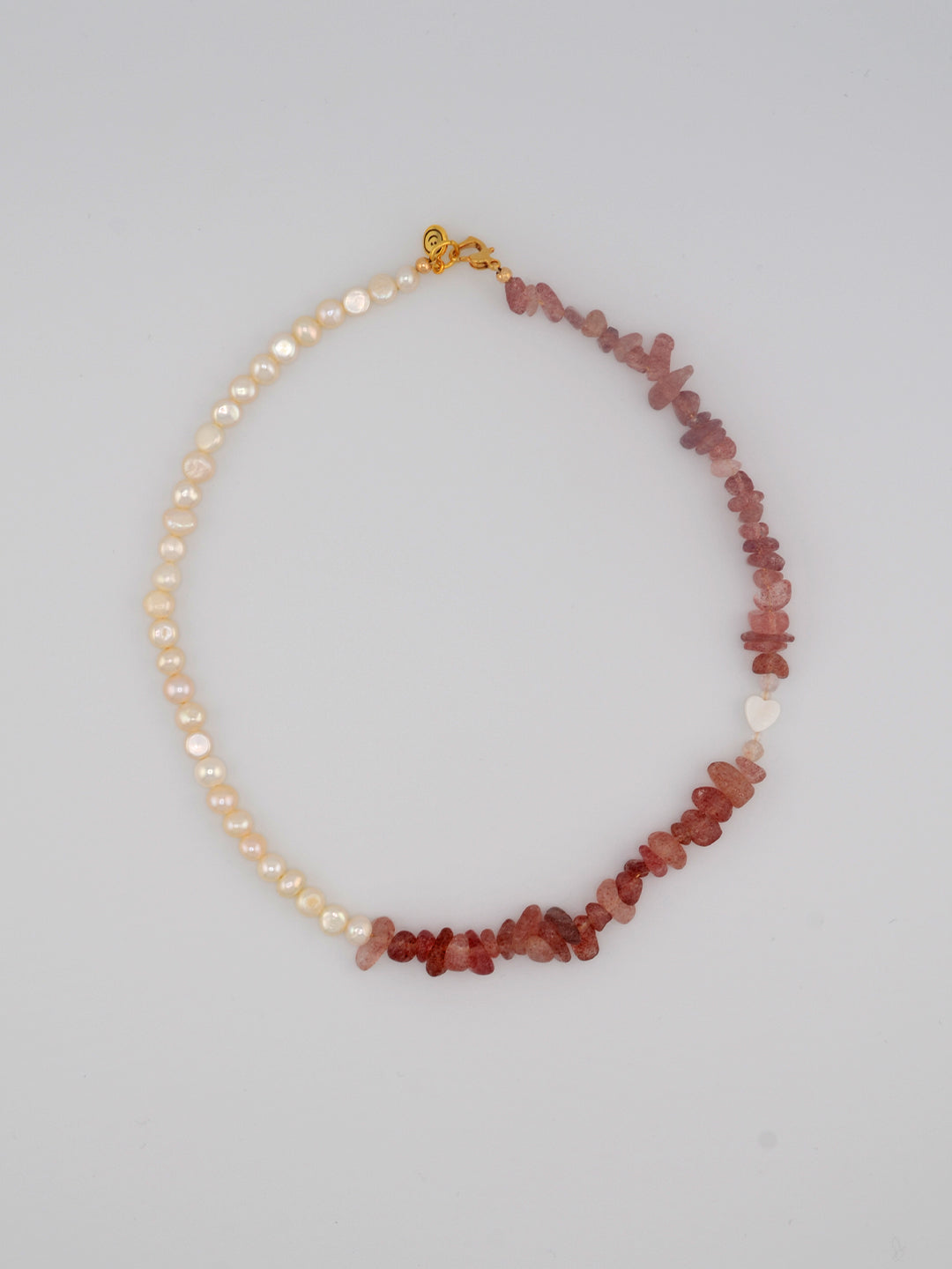 A striking handcrafted necklace showcasing a blend of lustrous pearls and vibrant strawberry quartz chips. The unique combination of smooth pearls and irregular crystal shapes adds character, while the gold-tone clasp ensures a secure and chic finish.