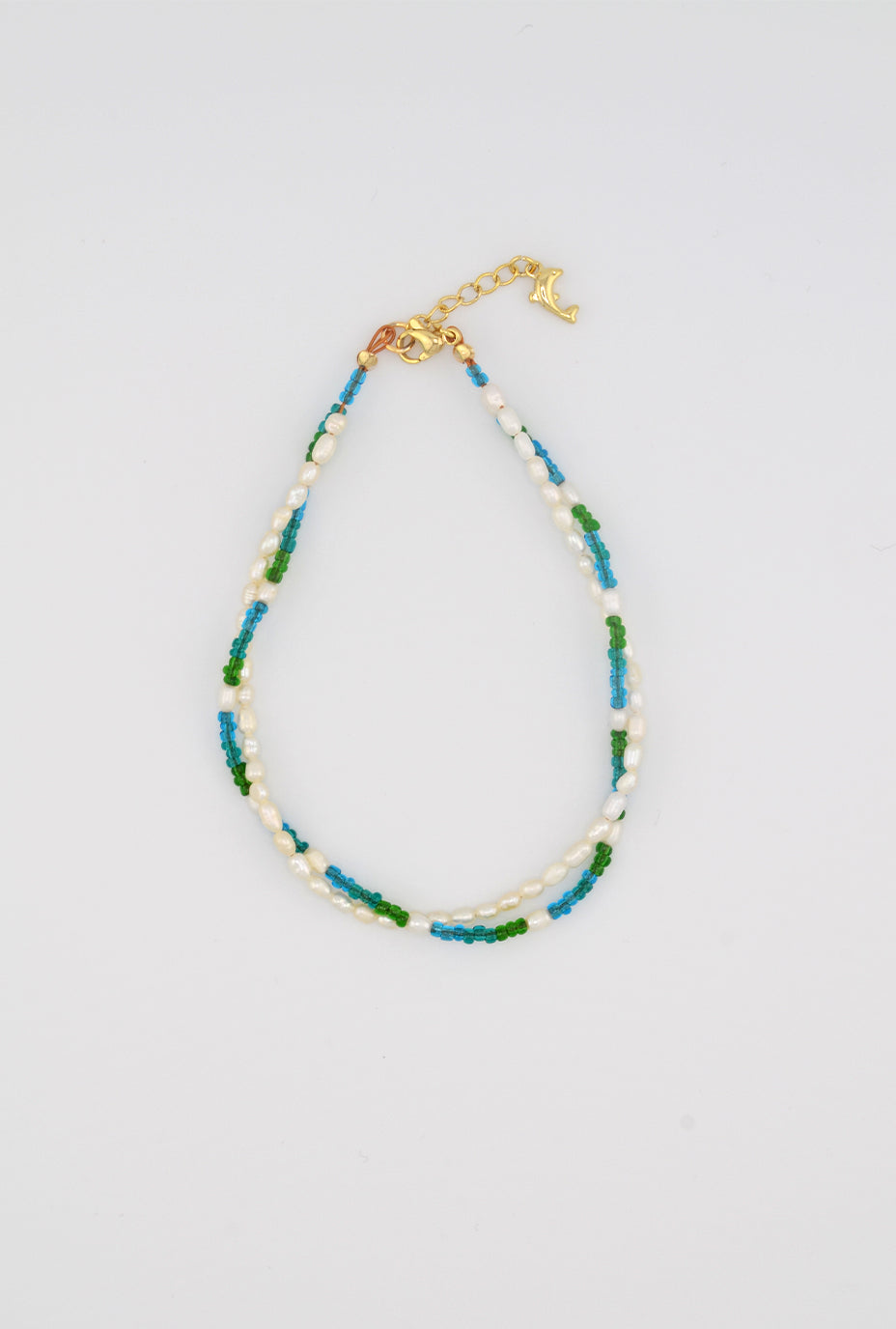 A simple yet elegant anklet with alternating freshwater pearls and vibrant green and blue glass beads, designed with a gold-tone dolphin charm to complete the beachy theme.
