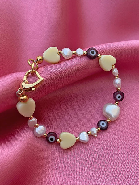 Bibi's Love Eyes Bracelet: Mix of acrylic yellow heart beads, small brown glass evil eye beads, gold plated spacer beads and freshwater pearls.